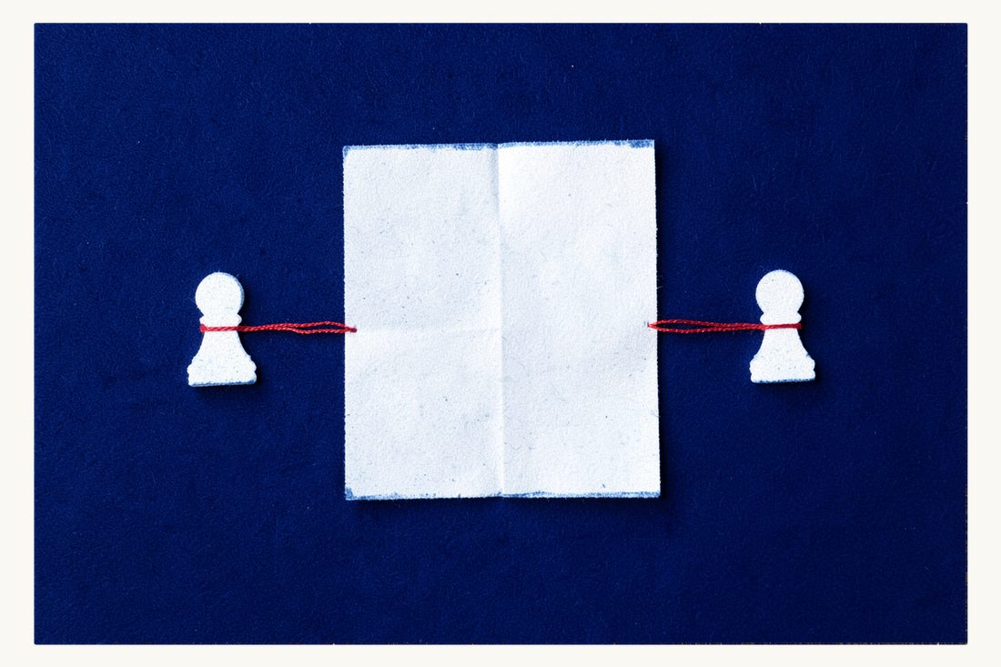 Mandatory mediation between landlord and tenant: two chess pawns facing each other either side of a folded blank sheet, joined by a red thread