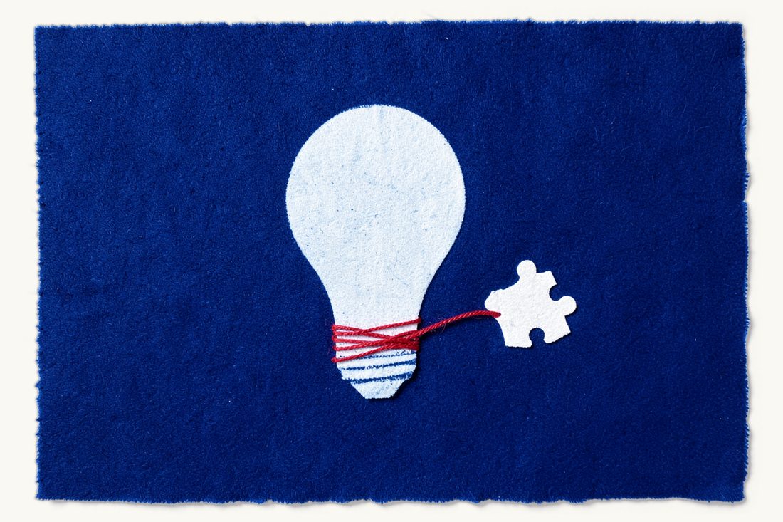 The technology undertaking rule in merger control: a large lightbulb with a red thread wound tightly around its base and pulling it toward a single jigsaw puzzle piece, cyanotype print