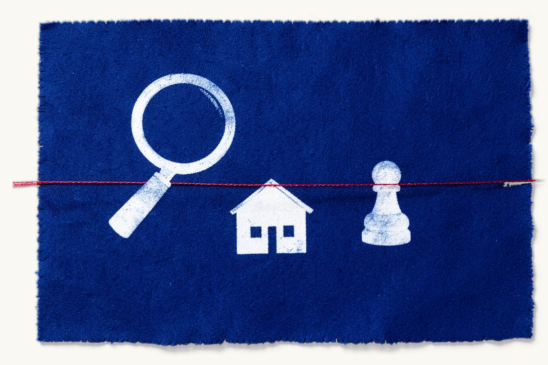Property due diligence before payment: a large magnifying glass over a small house with a pitched roof, the red thread stretched as a barrier holding a small pawn back, cyanotype print